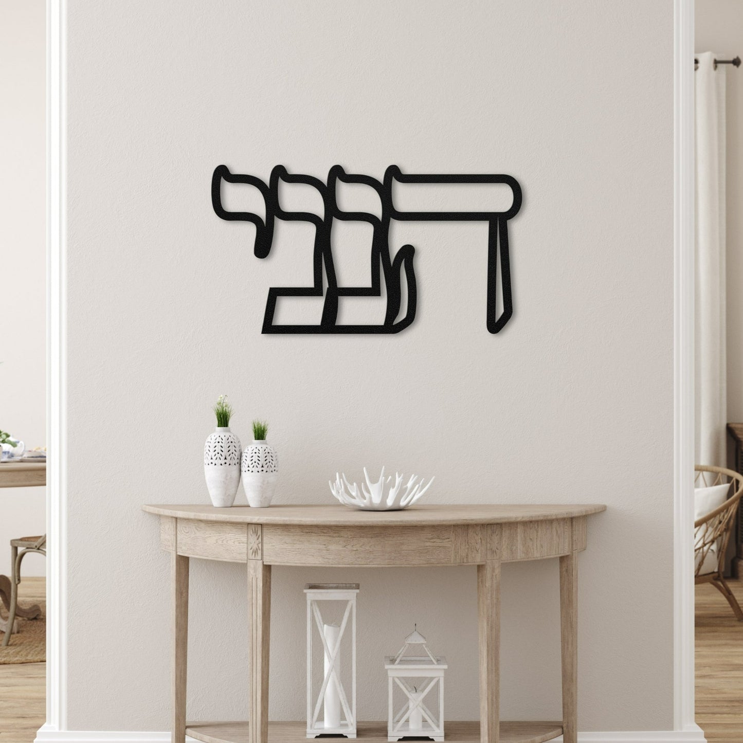 Elegant metal wall art featuring the Hebrew word 'הנני' (here I am), displayed in a serene, modern living space with minimalistic decor and neutral tones.