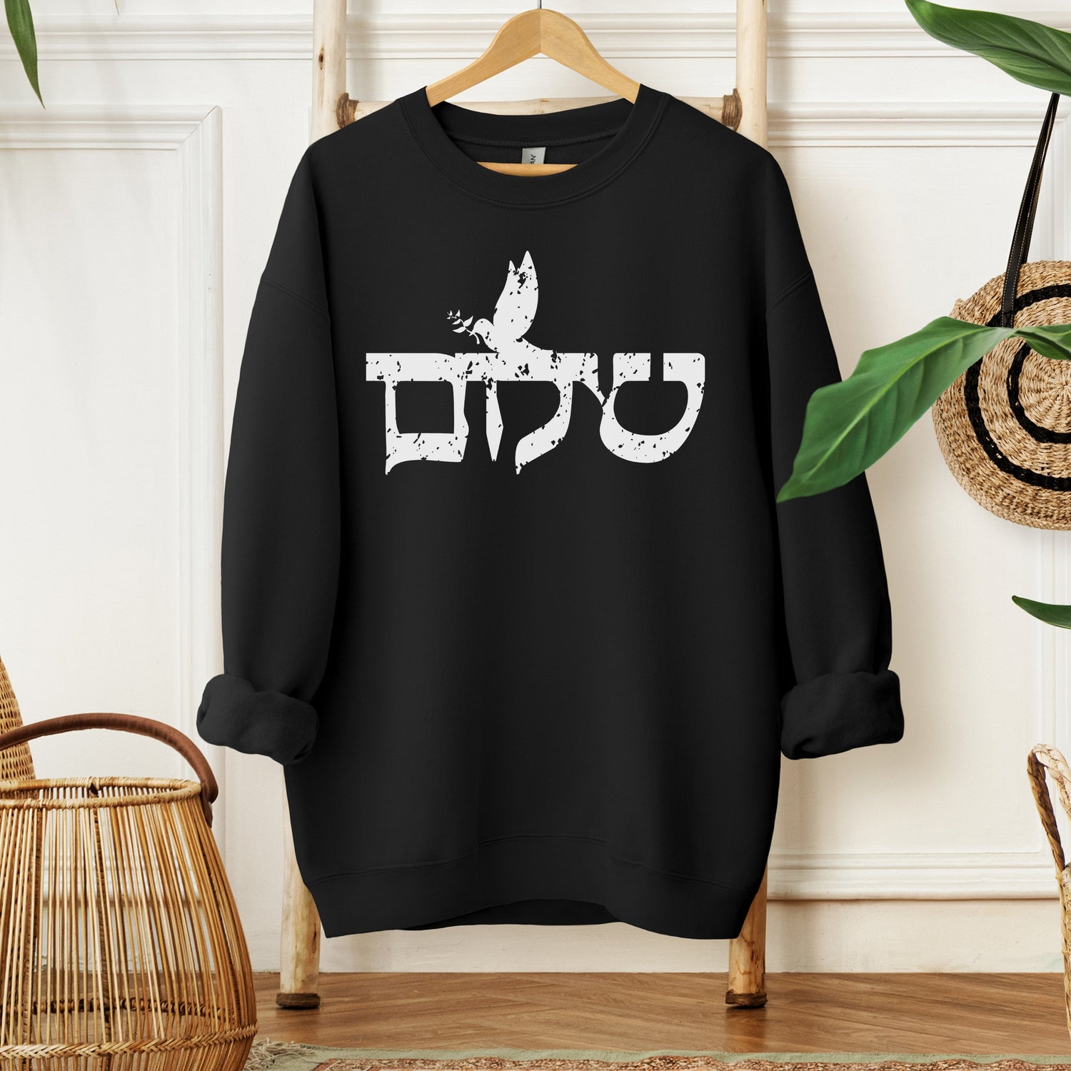 black sweatshirt with the word Shalom (peace in hebrew) with a flying dove attached to it in a distressed font