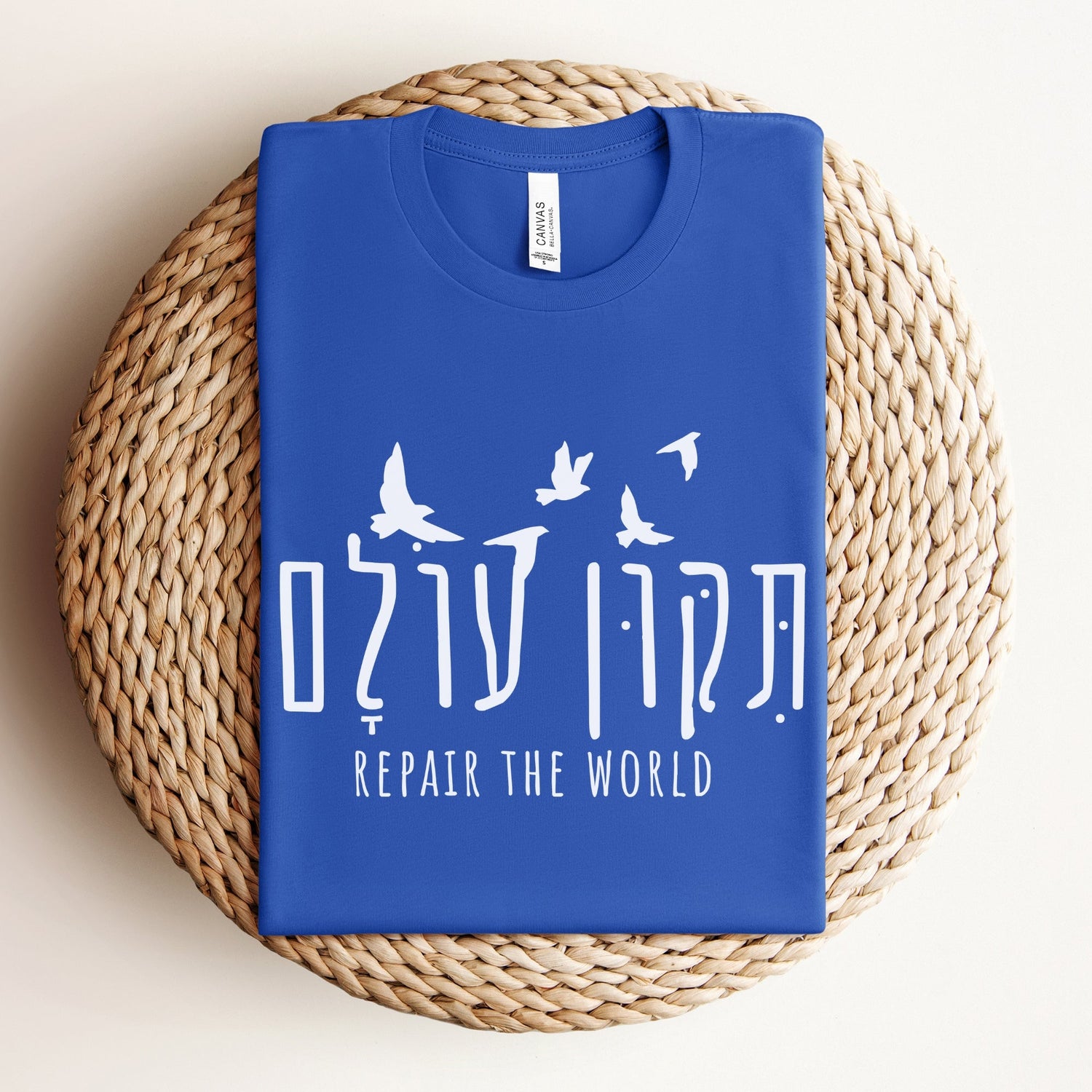 Blue t-shirt with the hebrew saying "תיקון עולם" (Tikkun olam - Repair the world in hebrew) in hebrew and english with flying doves