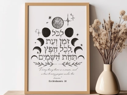 Framed wall art with the verse from Ecclesiastes 3:1 in Hebrew, featuring celestial designs, placed next to a vase with dried flowers.