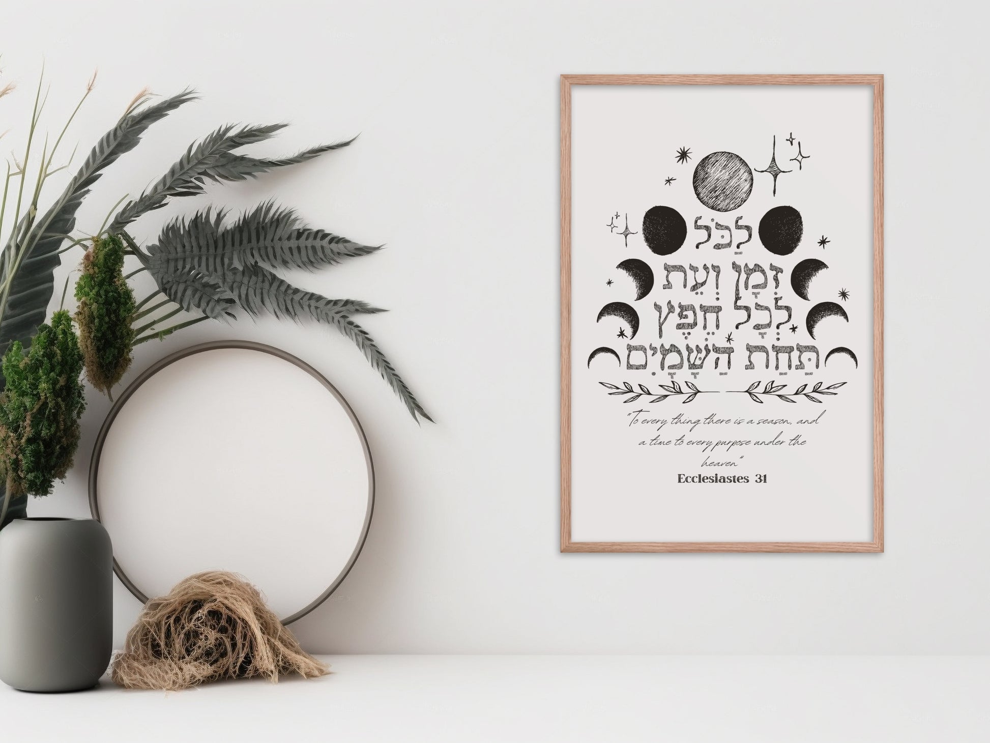 Framed wall art with the verse from Ecclesiastes 3:1 in Hebrew, featuring celestial designs, displayed next to a vase and dried botanical decor.