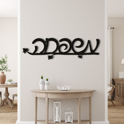 Black metal wall art with the Hebrew word 'משפחה' (Family) mounted on a light beige wall above a wooden console table.