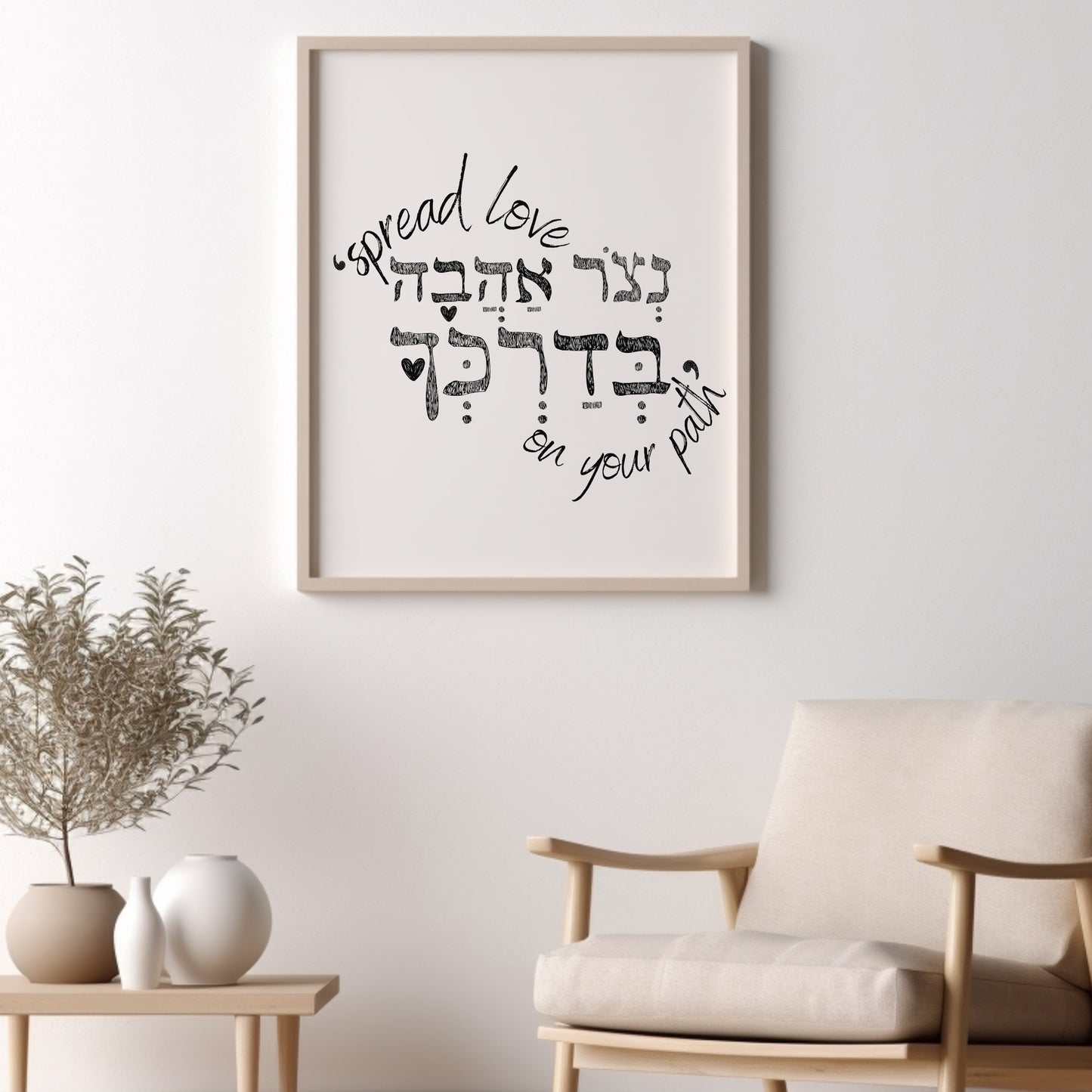 Framed wall art with the Hebrew phrase 'נצור אהבה בדרכך' (Spread love on your path), featuring a minimalist design, displayed above a chair with decorative plants nearby.