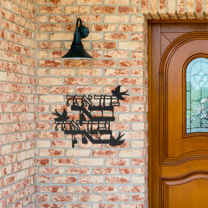 Stylish metal sign featuring "ברוך אתה בבאך וברוך אתה בצאתך" (Blessed are you in your coming and blessed are you in your going), perfect for enhancing a brick wall near the entrance.