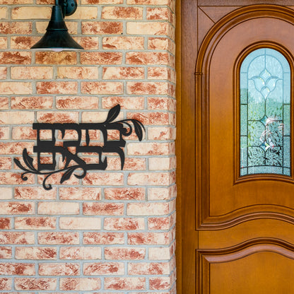 Powder-coated die-cut metal sign with the Hebrew phrase 'ברוכים הבאים' (Welcome), displayed on a brick wall near a wooden door.