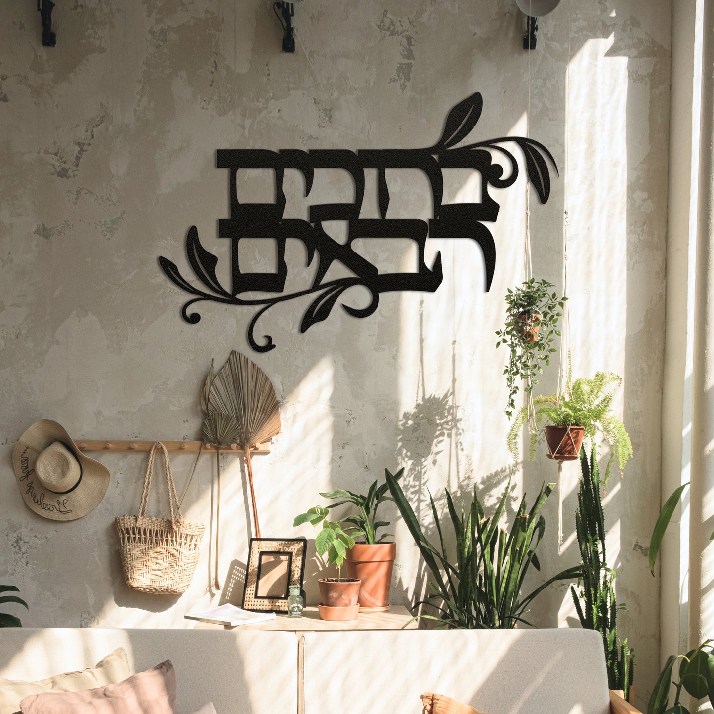 Powder-coated die-cut metal sign with the Hebrew phrase 'ברוכים הבאים' (Welcome), displayed in a cozy living space with indoor plants and natural light.