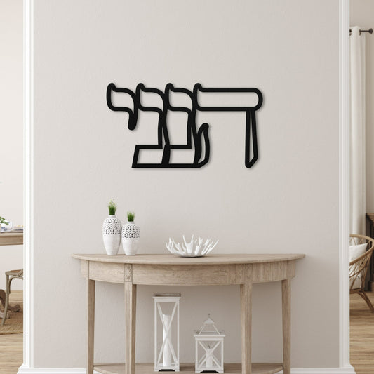 Elegant metal wall art featuring the Hebrew word 'הנני' (here I am), displayed in a serene, modern living space with minimalistic decor and neutral tones.