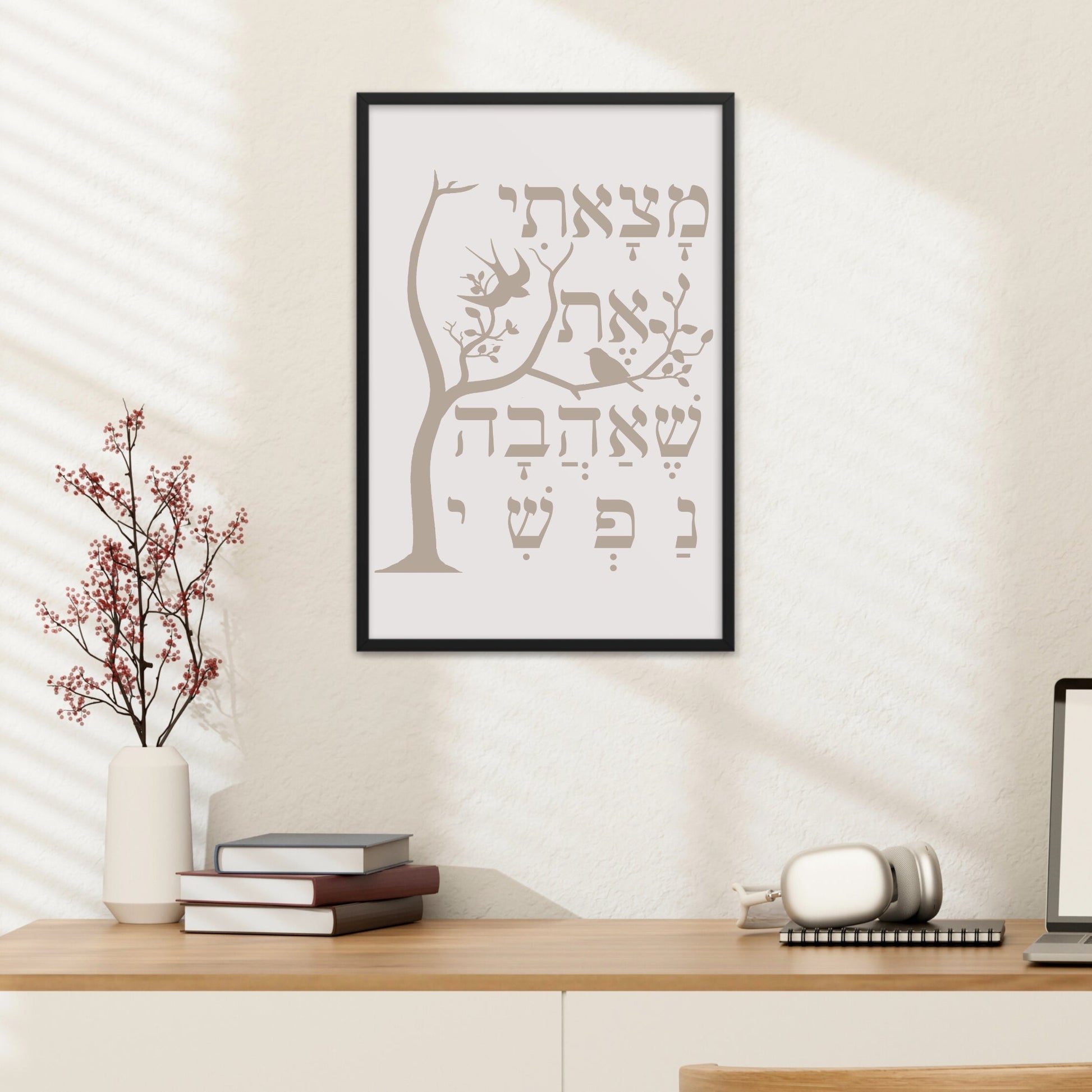 Framed wall art with a tree and the Hebrew verse 'מצאתי את שאהבה נפשי' (I have found the one whom my soul loves), hung above a desk with a lamp, books, and decorative branches.