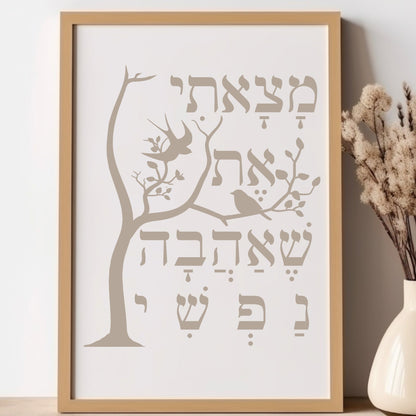 Framed wall art with a tree and the Hebrew verse 'מצאתי את שאהבה נפשי' (I have found the one whom my soul loves), placed next to a vase with dried flowers.
