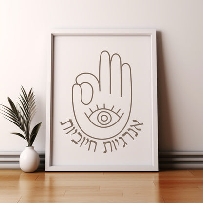 Framed wall art with the Hebrew phrase 'אנרגיות חיוביות' (Positive Energy) and a hamsa hand design, leaning against a wall beside a small potted plant.