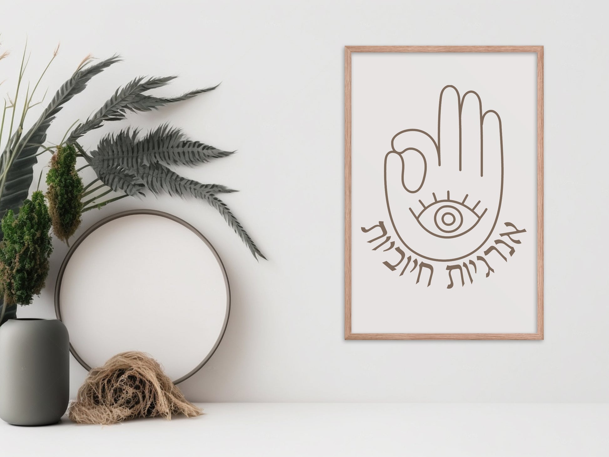 Framed wall art with the Hebrew phrase 'אנרגיות חיוביות' (Positive Energy) and a hamsa hand design, displayed next to a vase and dried botanical decor.