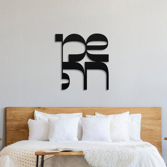 "שמחה" metal wall art displayed above a bed with white linens, featuring a modern design in black, symbolizing joy in Hebrew.