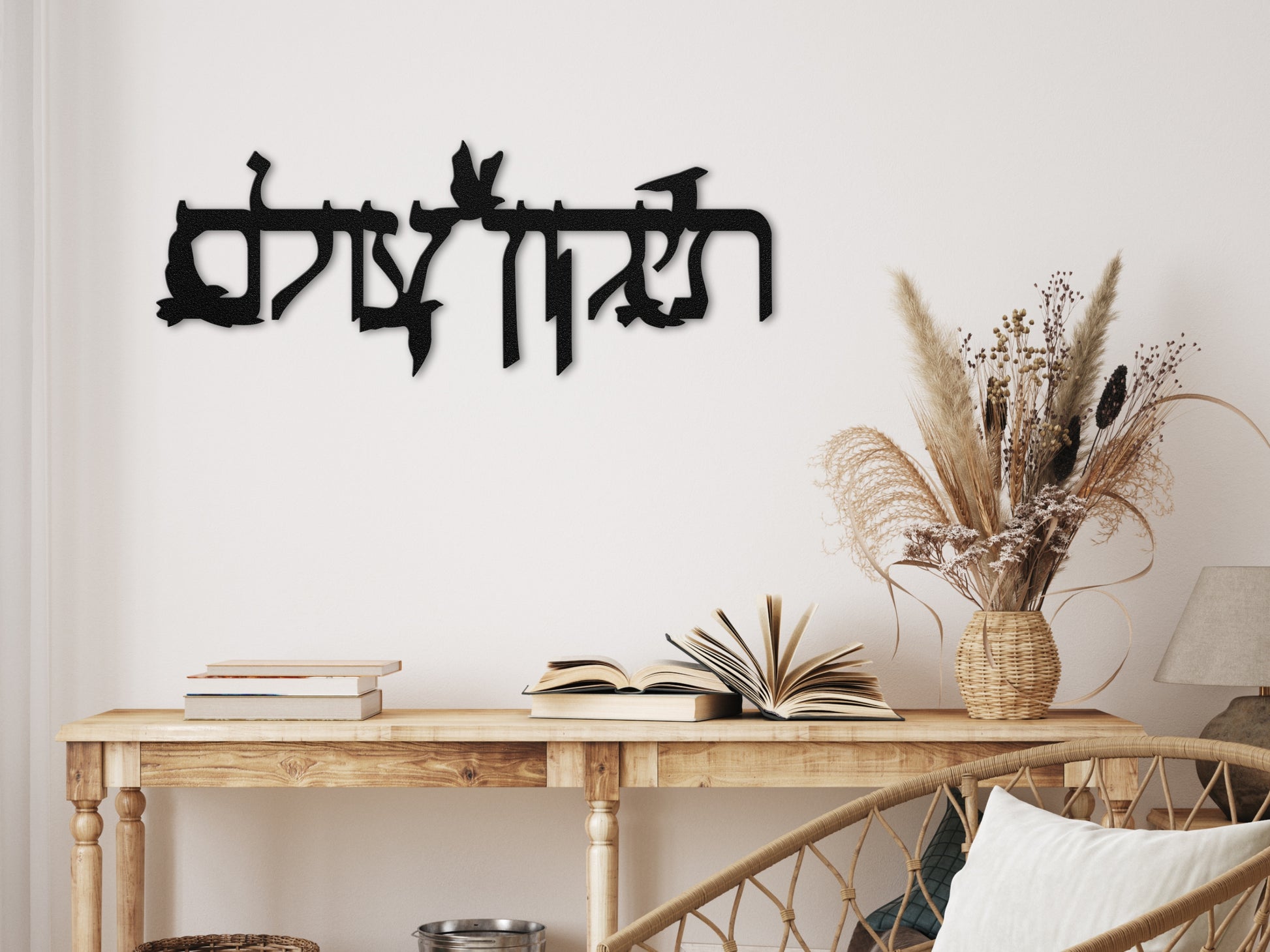 Metal sign "תיקון עולם" with flying doves placed above a rustic console with dried flowers and natural decor, enhancing a warm and inviting space.