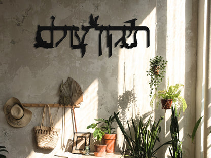 Metal sign "תיקון עולם" with flying doves displayed in a bohemian-style room, featuring a wicker chair, dried pampas grass, and a relaxed ambiance.